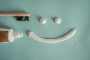 A creative arrangement of dental hygiene items forming a cheerful face on a light blue background.
